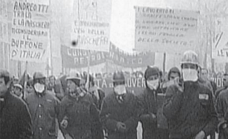 schwarz-weiss-foto mit einander untergehakten arbeitern. mit helmen und atemschutztüchern. viele transparente.